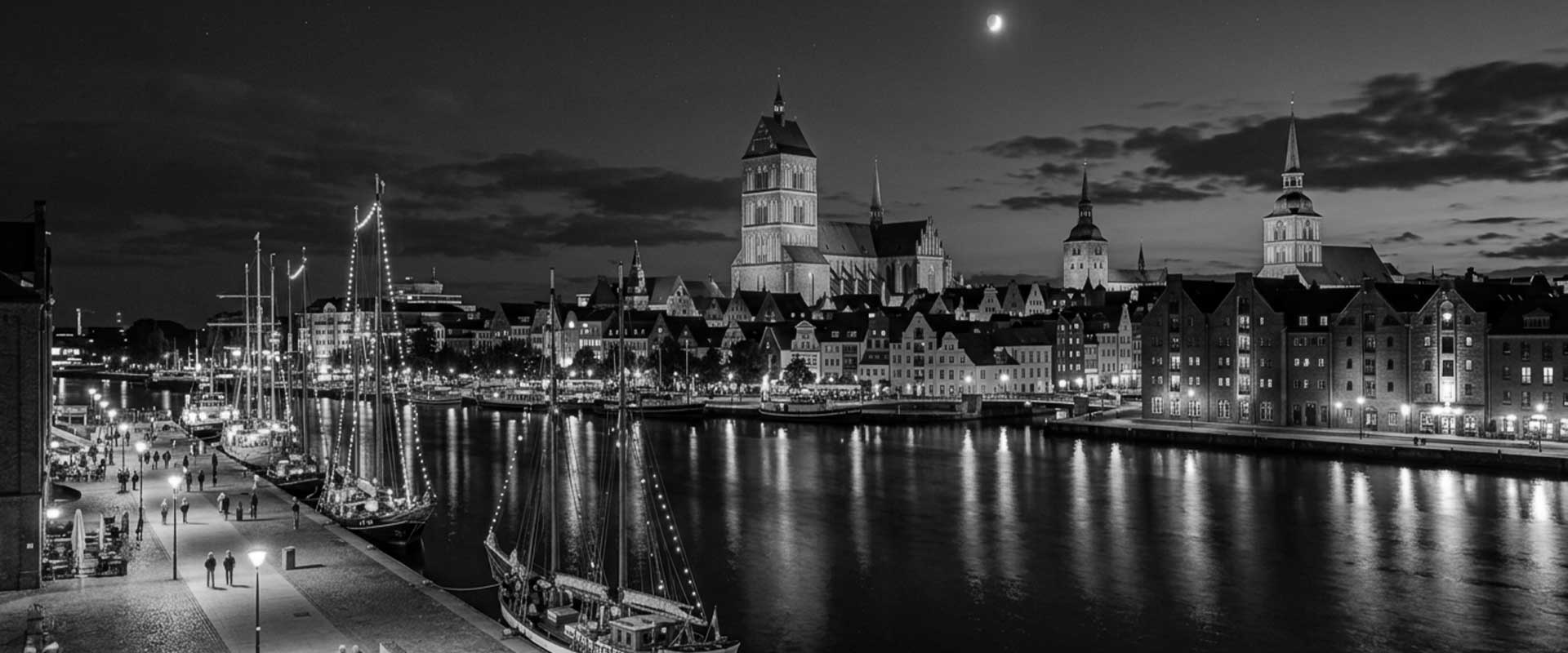 Blick auf eine nächtliche Stadt mit Wasser, beleuchteten Gebäuden und Türmen, ideal für Escort Service Werbung in einer eleganten Umgebung.
